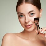 Beautiful woman using eyelash curler